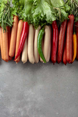 Various sausages with salad,  rosemary, and hot peppers on a concrete background. Concept of the theme of a picnic. Copy space.の写真素材