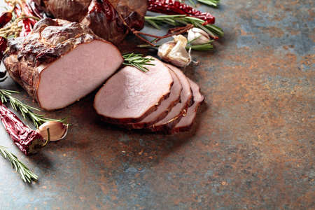 Smoked ham with rosemary, garlic, and pepper on a kitchen table. Copy space.