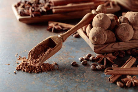 Chocolate truffles and spoon with cocoa powder. Candies with cinnamon, anise, and coffee beans on a...