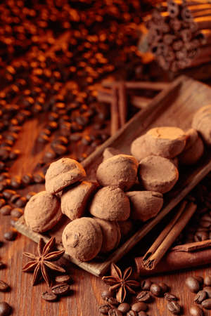 Delicious chocolate truffles with cinnamon, anise, and coffee beans on a old wooden table.の写真素材
