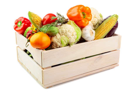 Various fresh vegetables in a wooden box isolated on a white background. Tomatoes, paprika, cauliflower, chili pepper, garlic, eggplant, cucumbers, corn, and rosemary are presented.の写真素材