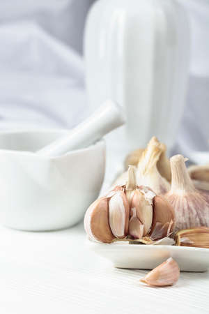 Fresh garlic bulbs on a white kitchen table. Copy space.の写真素材