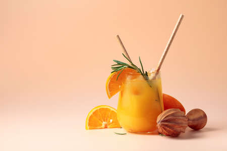 Orange juice with rosemary, and ice in a frozen glass. Orange juice and wooden squeezer.の写真素材