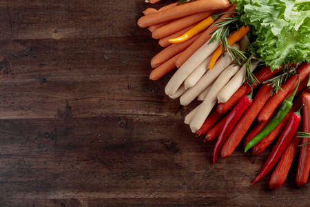 Various sausages with salad,  rosemary, and hot peppers on a wooden background. Concept of the theme of a picnic. Copy space.の写真素材
