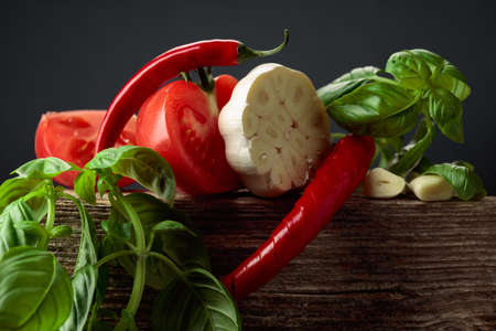 Ingredients for making spicy tomato sauce. Fresh tomatoes, red pepper, garlic, and basil on an old wooden table.の写真素材