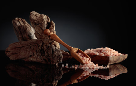 Pink salt with an old snag on a black reflective background. The concept of the theme is natural ingredients and spa.の写真素材