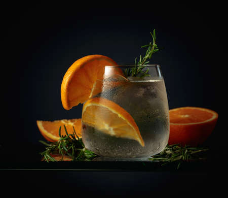 Cocktail with ice, orange, and rosemary in a frozen glass.の写真素材