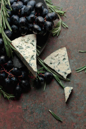 Blue cheese with grapes, and rosemary, on vintage background. Top view.の写真素材