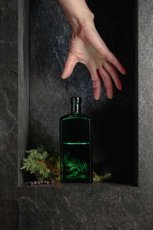 Hand reach for a vintage bottle of gin. A concept image on the theme of expensive drinks.の写真素材