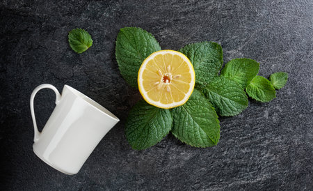 White mug, lemon, and mint leaves, top view.