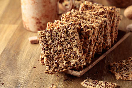 Crispy crackers with sunflower seeds and flax seeds on a wooden table.