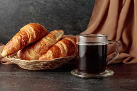 Freshly baked croissants and black coffee on a kitchen table.の写真素材