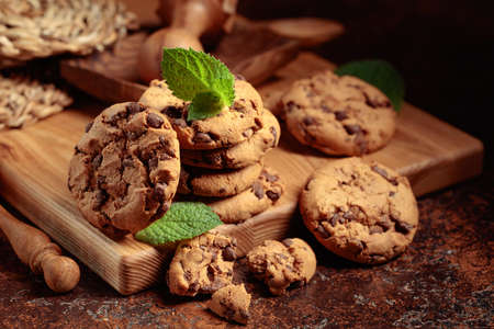 Freshly baked chocolate cookies with mint on a brown background.の写真素材