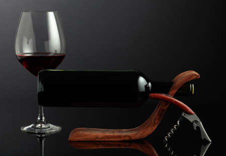 Bottle of red wine in a wooden bottle holder on a black reflective background. Copy space.の写真素材