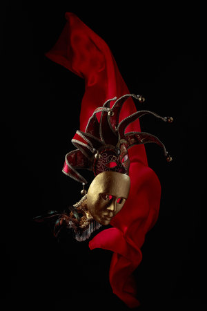 Old carnival masks on a black background with flutters red cloth.の写真素材