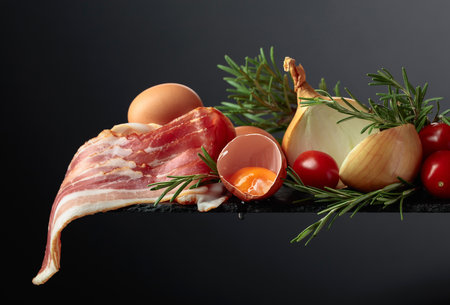Smoked bacon with eggs, tomatoes, onions and rosemary. Copy space.の写真素材