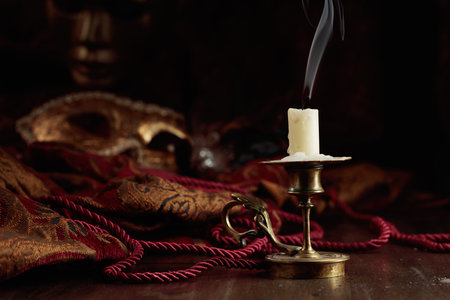 Still life with an extinguished candle in an old brass candlestick and carnival masks.の写真素材