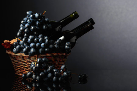 Red wine and blue grapes on a black reflective background. Focus on a foreground.の写真素材