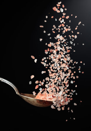 Pink Himalayan salt is poured with a spoon. Himalaya salt on a dark background. Copy space.の写真素材
