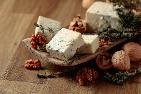 Blue cheese with walnuts and thyme on an old wooden table.