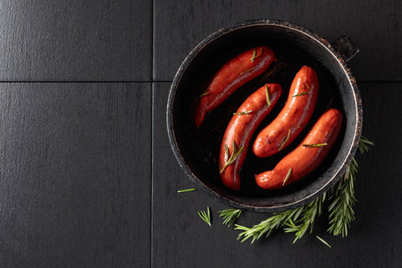Roasted Bavarian sausages with rosemary in an old black pan. Copy space.の写真素材
