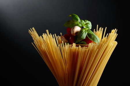 Raw spaghetti with tomato, garlic, and basil on a black background.の写真素材