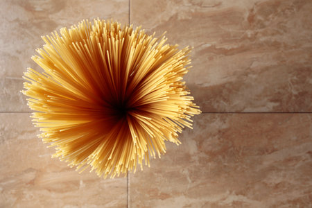 Yellow long spaghetti on a brown ceramic background. Yellow Italian pasta. Raw spaghetti bolognese. Italian food and menu concept. Top view with copy space.の写真素材