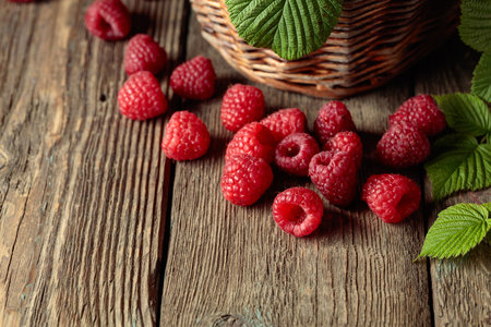 Ripe juicy raspberries with leaves on an old wooden table.