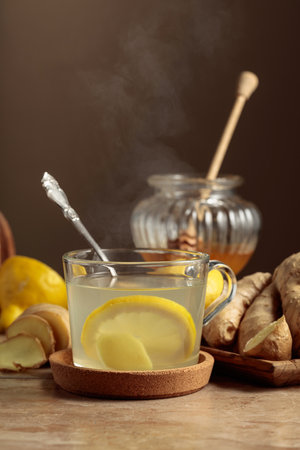 Ginger tea with lemon and honey on a beige kitchen table.の写真素材