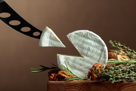 Brie cheese with walnuts, thyme, and rosemary on a wooden table. Copy space.の写真素材