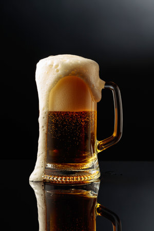 Mug of beer on a black reflective background.の写真素材