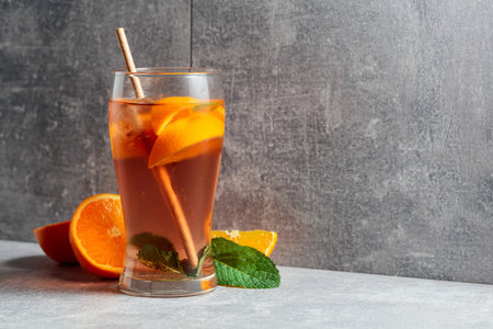 Iced tea with ice, mint, and orange. A cold refreshing drink with ingredients on a grey background. Copy space.の写真素材