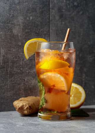 Iced tea with ice, mint, ginger, and lemon. A cold refreshing drink with ingredients on a grey background.の写真素材