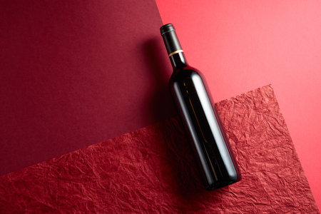 Bottle of red wine on a red background.Red background with different textures and shades. Top view, copy space.の写真素材
