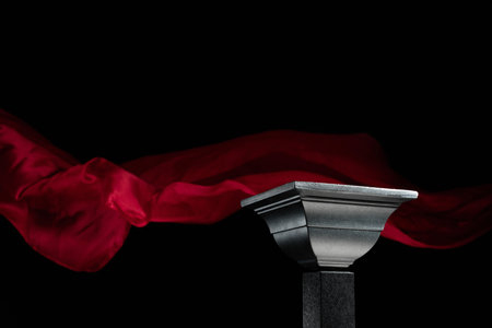 Luxury black podium on a background of waving red atlas curtain. Perfect platform for showing your products on a dark background.の写真素材