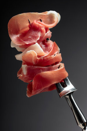 Thin slices of prosciutto on a fork.の写真素材
