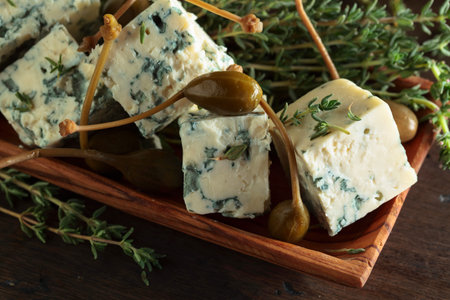Blue cheese, capers and branches of thyme on a wooden table.の写真素材
