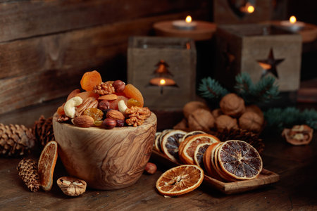 Dried fruits and assorted nuts on an old wooden table. Christmas still-life with spruce branches and burning candles in old lanterns.の写真素材