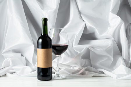 Red wine on a white wooden tfble. In the background white satin curtain.の写真素材