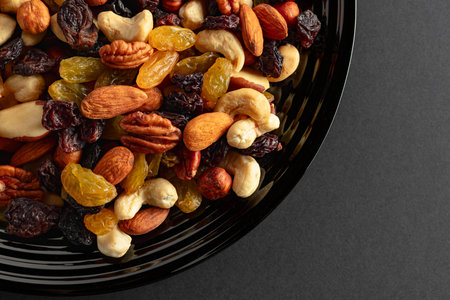 Mix of dried nuts and raisins on a black background. Top view. Copy space.の写真素材