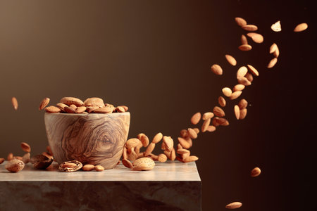 Almond nuts are poured into a wooden bowl. Brown background with copy space.の写真素材