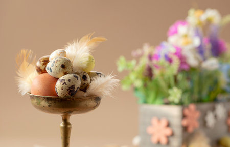 Easter composition with eggs, feathers, and spring flowers on a beige background. Selective focus.