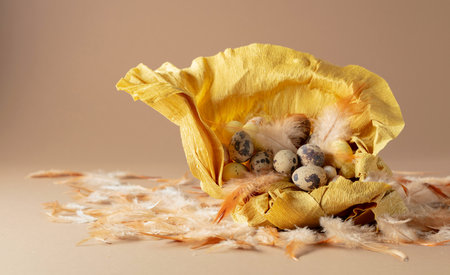 Crepe paper nest with easter eggs and feathers on a beige background.の写真素材
