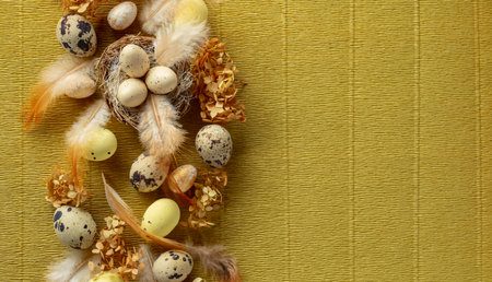 Easter composition with quail eggs, feathers, and dried flowers. Top view. Gold background with copy...