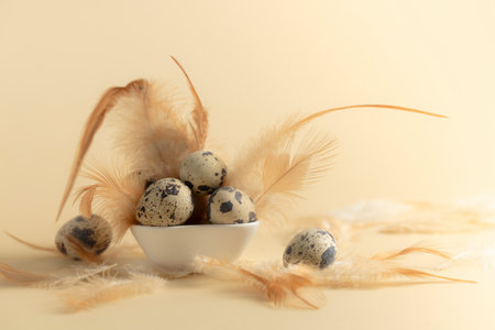Quail eggs and feathers on a yellow background. Copy space.