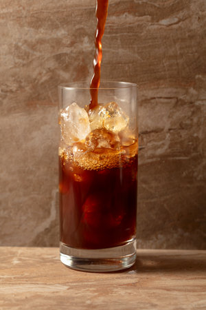 Black iced coffee on a beige ceramic table.