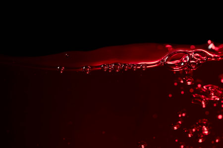Red wine on a black background, abstract splashing. Macro shot. Copy space.