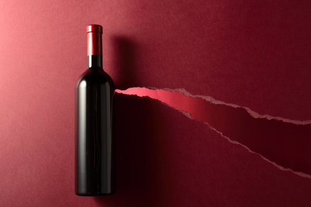 Bottle of red wine on a dark red background. Top view. Copy space.の写真素材