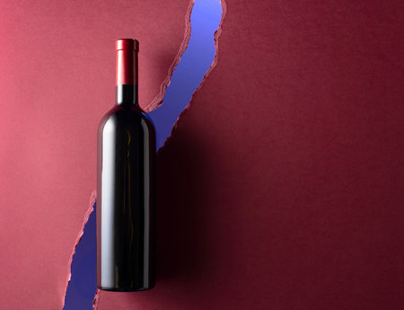 Bottle of red wine on a dark red background. Top view. Copy space.の写真素材