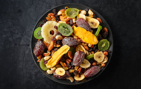 Dried tropical fruits with various nuts and raisins on a black background. Top view.の写真素材